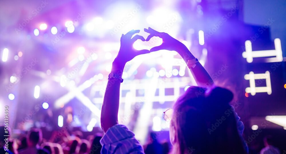heart-shaped-hands-at-concert-loving-the-artist-and-the-festival-music-concert-with-lights-and-silhouette-of-people-enjoying-the-concert-stockpack-adobe-stock